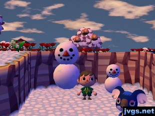 A large snowman next to a smaller snowman, as Yuka walks by.