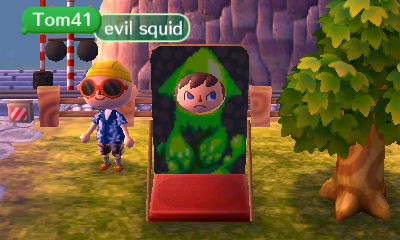 Tom calls me an evil squid as I make an angry face while using the face-cutout standee with a Splatoon squid design on it.