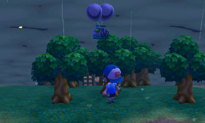 A silver slingshot, on two silver balloons, floats overhead in the rain.