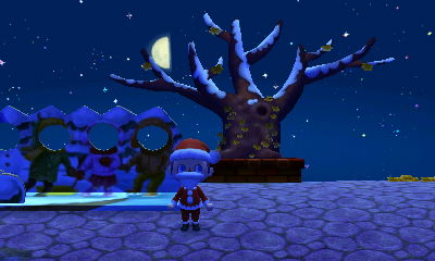 The winter solstice face-cutout standee and a bare town tree at night.